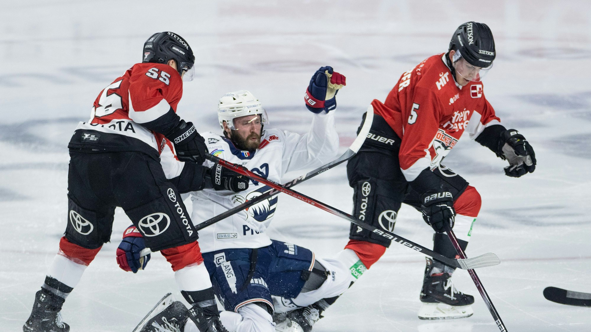 Eishockey: DEL, Kölner Haie - Adler Mannheim, Hauptrunde, 52. Spieltag, Lanxess Arena. Kölns Carter Proft (l) sowie Robin van Calster (r) und Mannheims Keaton Thompson versuchen an den Puck zu kommen.