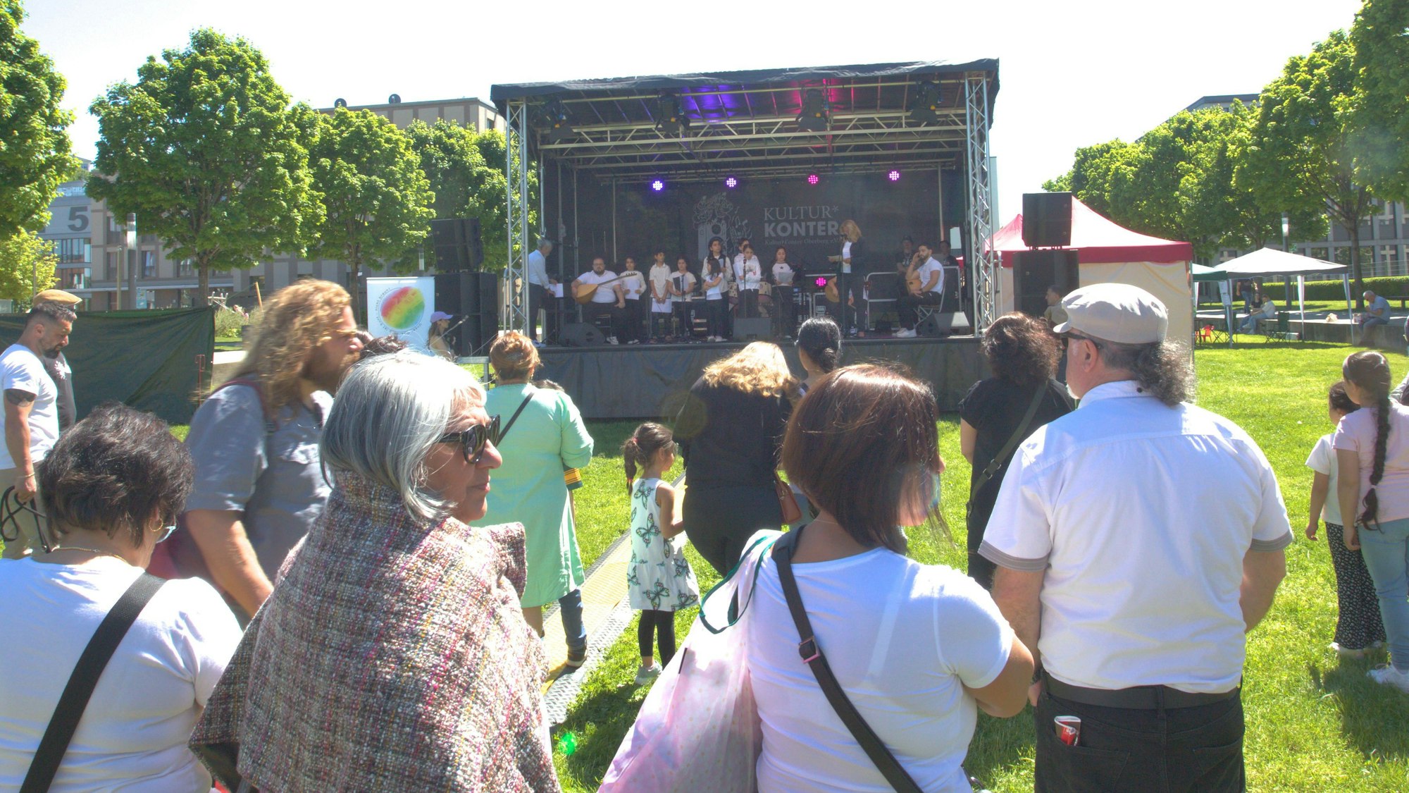 Vor der aufgebauten Bühne im Gummersbacher Stadtgarten, hören Besucher des Festivals dem Chor der anatolischen Stimme zu.