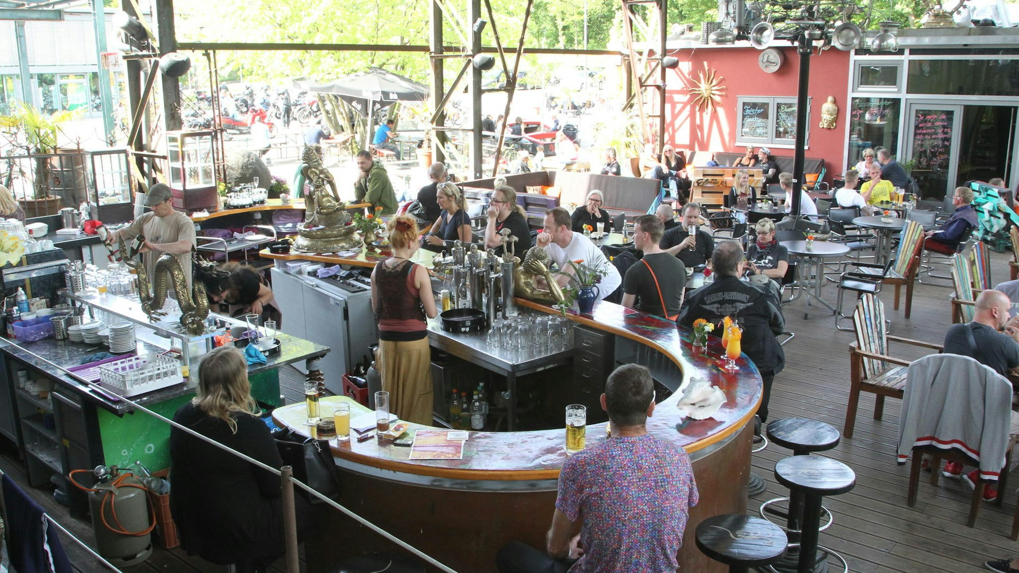 Blick auf den Außenbereich eines Restaurants mit einer großen Theke, Tischen und Stühlen.